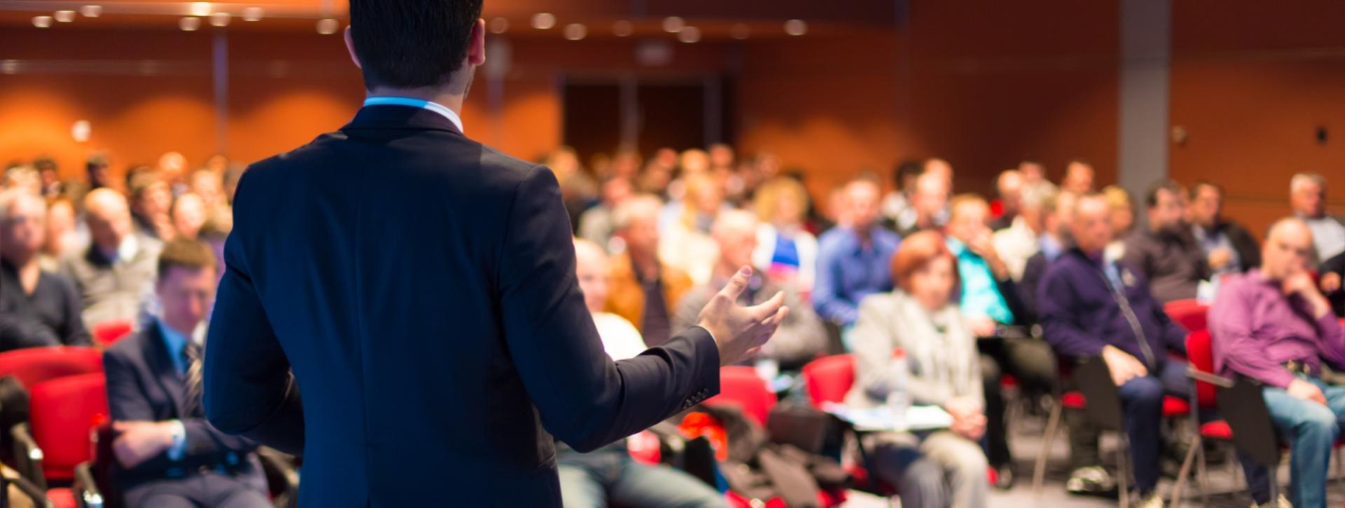 Un oratore parla a una folla durante una conferenza in una sala.