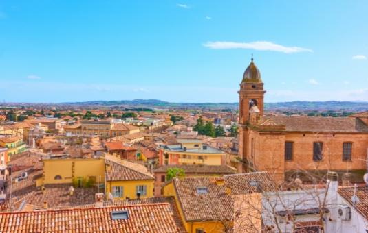 Panorama di una città italiana con tetti e una chiesa storica.