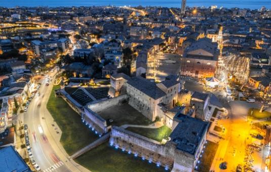 Vista notturna di una città italiana con edifici storici e strade illuminate.